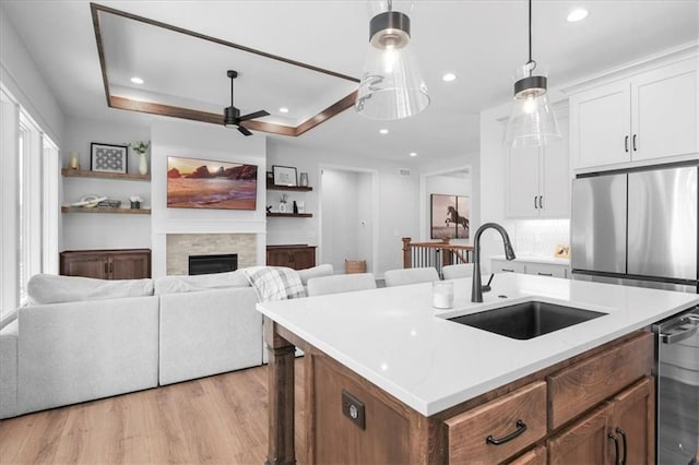 1161 SW Whitby Dr, Lees Summit, MO 64083 - kitchen featuring ceiling fan, light wood-style floors, a fireplace, white cabinets, and a center island with sink