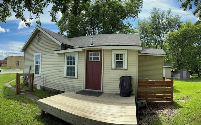 108 W Main St, Arma, KS 66712 - rear view of property featuring a lawn, a wooden deck, and a storage unit