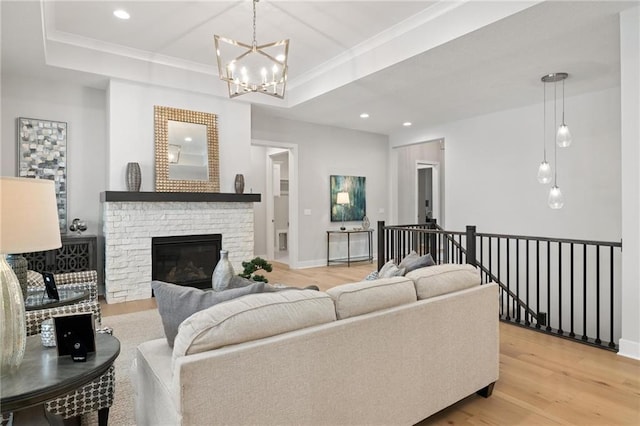 8164 Roundtree St, Lenexa, KS 66220 - living area featuring light wood-type flooring, ornamental molding, a chandelier, a glass covered fireplace, and a raised ceiling