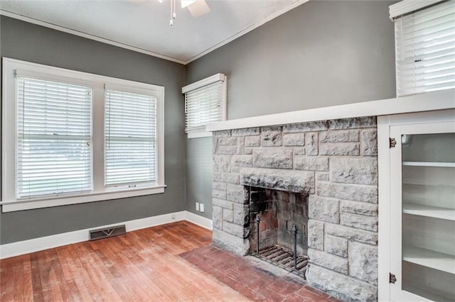 1401 E Mechanic Ave, Independence, MO 64050 - unfurnished living room with a stone fireplace, crown molding, wood finished floors, and a ceiling fan