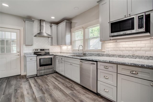 1401 E Mechanic Ave, Independence, MO 64050 - kitchen with wall chimney range hood, stainless steel appliances, decorative backsplash, light stone counters, and recessed lighting