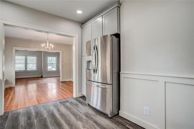 1401 E Mechanic Ave, Independence, MO 64050 - kitchen featuring stainless steel fridge with ice dispenser, a chandelier, dark wood-style floors, a decorative wall, and wainscoting