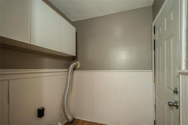 230 N 300th Rd, Overbrook, KS 66524 - laundry area featuring cabinet space, a wainscoted wall, a textured ceiling, and wood finished floors