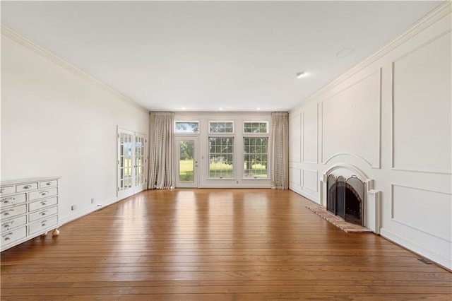14908 E Pawhuska Rd, Nevada, MO 64772 - unfurnished living room with a fireplace with raised hearth, healthy amount of natural light, a decorative wall, wood-type flooring, and crown molding
