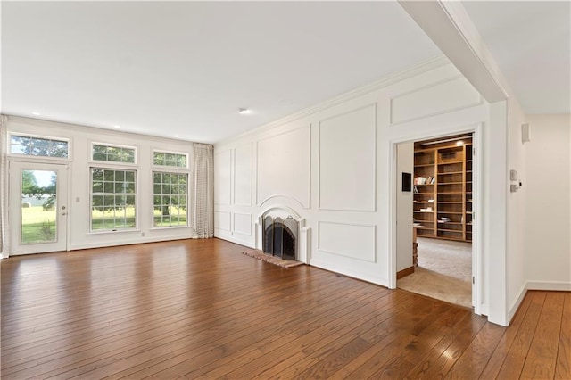 14908 E Pawhuska Rd, Nevada, MO 64772 - unfurnished living room with a fireplace with raised hearth, dark wood-type flooring, ornamental molding, and built in features