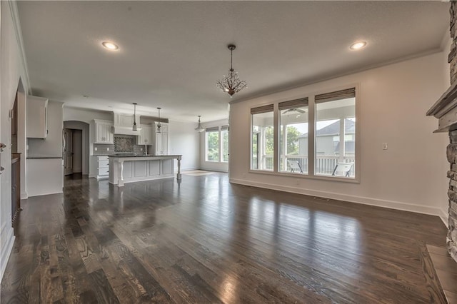 14017 Haskins St, Overland Park, KS 66221 - unfurnished living room with ornamental molding, a stone fireplace, recessed lighting, arched walkways, and dark wood finished floors