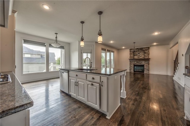 14017 Haskins St, Overland Park, KS 66221 - kitchen with appliances with stainless steel finishes, a stone fireplace, dark wood-style flooring, a center island with sink, and open floor plan