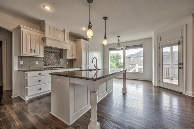 14017 Haskins St, Overland Park, KS 66221 - kitchen featuring decorative backsplash, a center island with sink, dark wood finished floors, decorative light fixtures, and a textured ceiling
