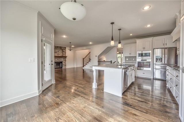 14017 Haskins St, Overland Park, KS 66221 - kitchen featuring stainless steel appliances, open floor plan, a stone fireplace, recessed lighting, and white cabinetry