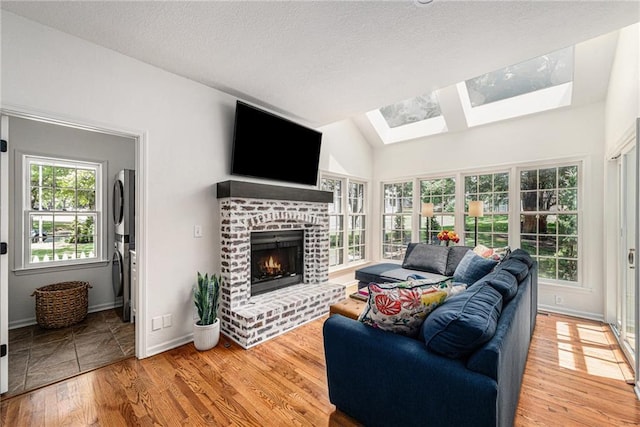 11401 Cedar St, Leawood, KS 66211 - living area featuring a fireplace, wood finished floors, a skylight, vaulted ceiling, and a textured ceiling