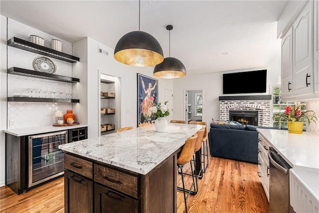 11401 Cedar St, Leawood, KS 66211 - kitchen featuring wine cooler, open shelves, light wood-type flooring, stainless steel dishwasher, and decorative backsplash