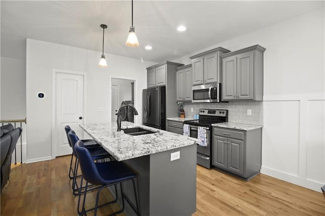 1013 SE Beatty Ct, Blue Springs, MO 64014 - kitchen featuring gray cabinetry, stainless steel appliances, a center island with sink, a kitchen bar, and tasteful backsplash