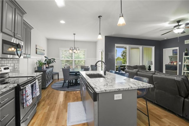 1013 SE Beatty Ct, Blue Springs, MO 64014 - kitchen featuring appliances with stainless steel finishes, open floor plan, a kitchen breakfast bar, light wood-type flooring, and recessed lighting