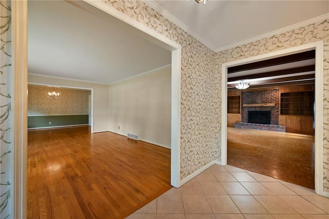 4411 W 89th St, Prairie Village, KS 66207 - tiled spare room with a chandelier, a brick fireplace, crown molding, and wallpapered walls