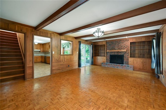 4411 W 89th St, Prairie Village, KS 66207 - unfurnished living room featuring wooden walls, beam ceiling, a brick fireplace, stairway, and built in features