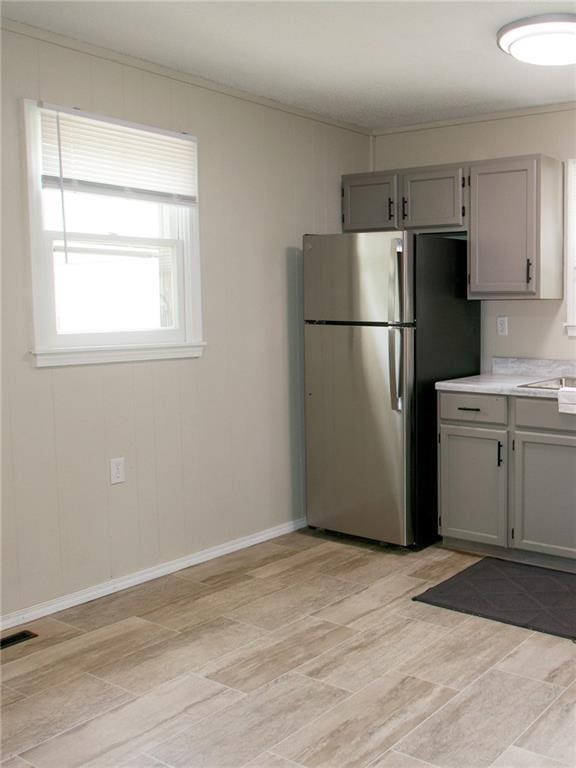 715 N Warren St, Warrensburg, MO 64093 - kitchen featuring freestanding refrigerator, gray cabinets, light countertops, and ornamental molding