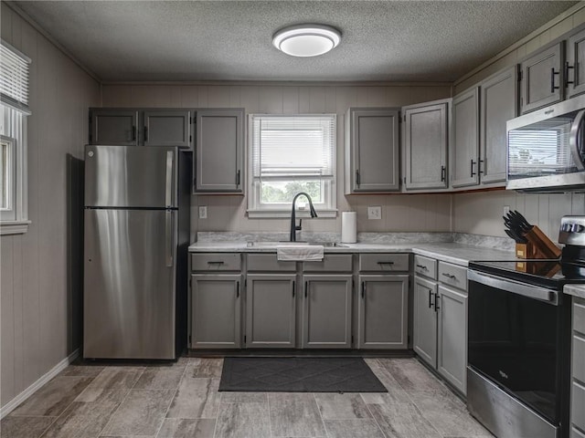 715 N Warren St, Warrensburg, MO 64093 - kitchen featuring appliances with stainless steel finishes, gray cabinets, light countertops, a textured ceiling, and wooden walls