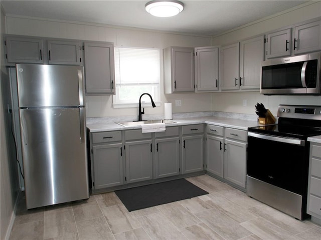 715 N Warren St, Warrensburg, MO 64093 - kitchen with appliances with stainless steel finishes, gray cabinetry, light countertops, and ornamental molding