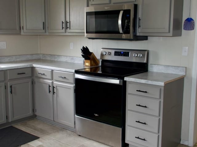 715 N Warren St, Warrensburg, MO 64093 - kitchen featuring stainless steel appliances, light countertops, light tile patterned flooring, and gray cabinetry