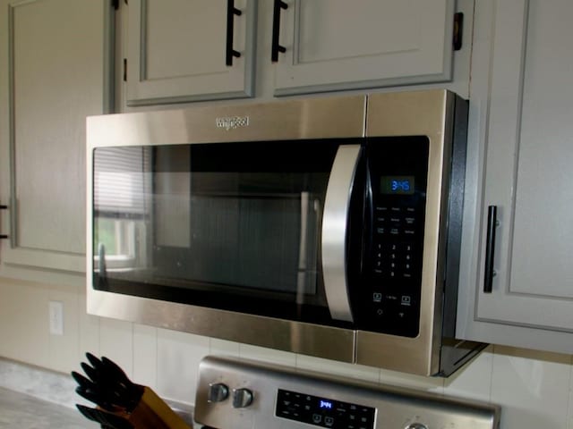 715 N Warren St, Warrensburg, MO 64093 - kitchen view of stainless steel microwave, backsplash, range, and tile counters