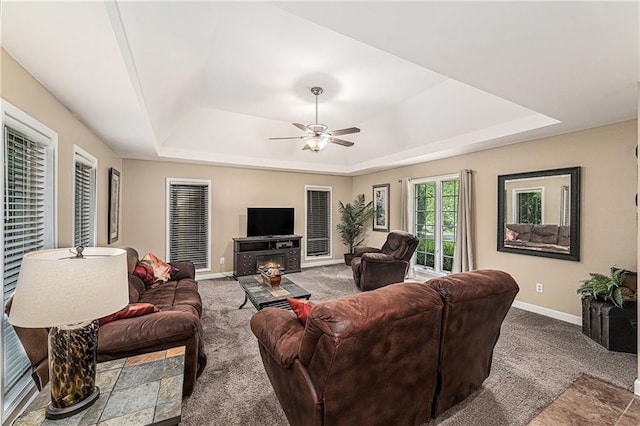807 NW Bent Tree Dr, Lees Summit, MO 64081 - living area with a raised ceiling, carpet, ceiling fan, and a warm lit fireplace