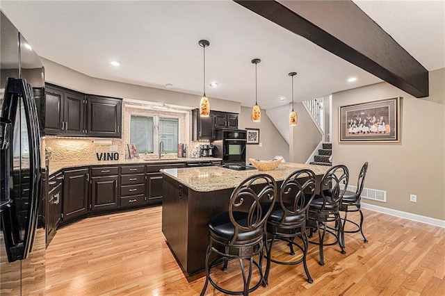 807 NW Bent Tree Dr, Lees Summit, MO 64081 - kitchen with freestanding refrigerator, a center island, light wood-style flooring, a kitchen breakfast bar, and decorative backsplash