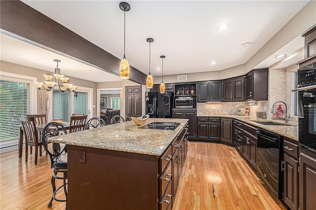 807 NW Bent Tree Dr, Lees Summit, MO 64081 - kitchen featuring black appliances, a breakfast bar, a chandelier, light wood-style floors, and recessed lighting