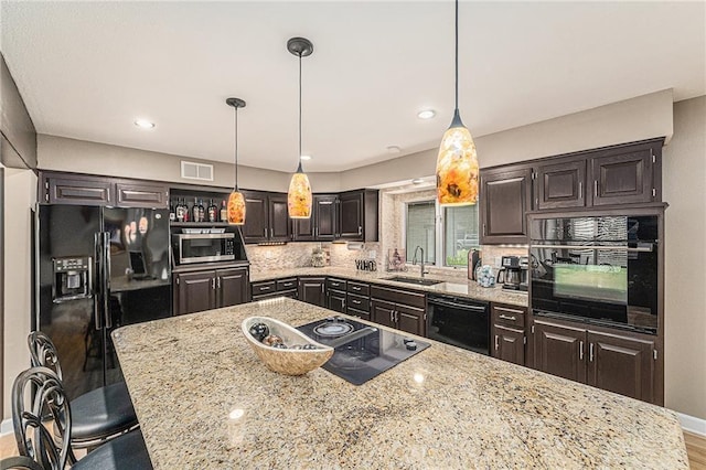 807 NW Bent Tree Dr, Lees Summit, MO 64081 - kitchen featuring black appliances, backsplash, light stone countertops, a kitchen bar, and decorative light fixtures