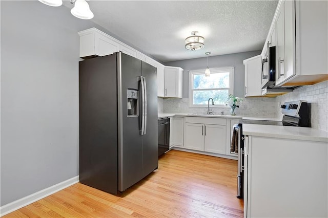 809 E 110th St, Kansas City, MO 64131 - kitchen with stainless steel appliances, backsplash, white cabinets, light wood finished floors, and a textured ceiling
