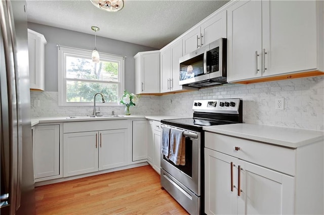 809 E 110th St, Kansas City, MO 64131 - kitchen with appliances with stainless steel finishes, light countertops, white cabinets, decorative backsplash, and light wood-type flooring