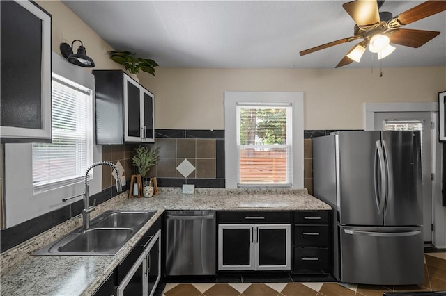 3230 Bellefontaine Ave, Kansas City, MO 64128 - kitchen with stainless steel appliances, ceiling fan, dark cabinets, glass insert cabinets, and light stone countertops