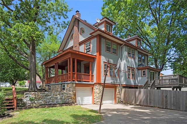 1535 W 75th St, Kansas City, MO 64114 - view of front of home with an attached garage, a chimney, stone siding, asphalt driveway, and a balcony
