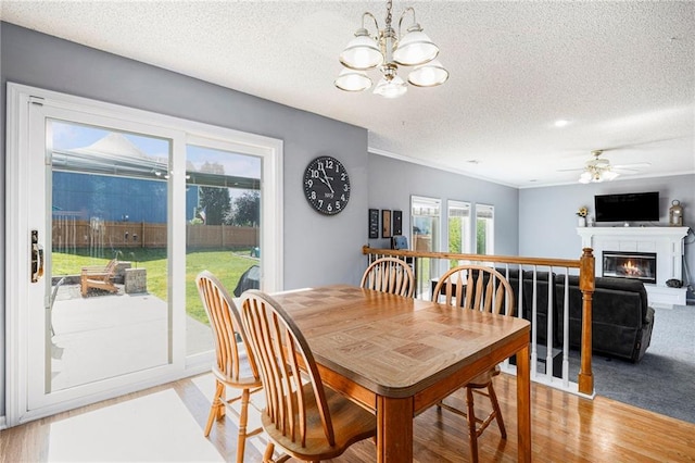 2417 SW Woodhaven Ln, Lees Summit, MO 64082 - dining room with a chandelier, a textured ceiling, a glass covered fireplace, ceiling fan, and light wood-style floors