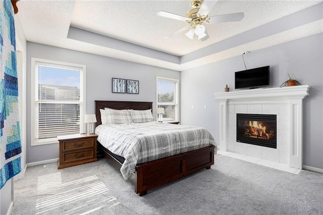 2417 SW Woodhaven Ln, Lees Summit, MO 64082 - bedroom featuring a textured ceiling, carpet floors, a tiled fireplace, a tray ceiling, and ceiling fan