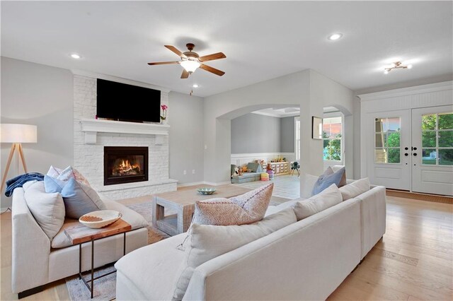 20487 W 108th St, Olathe, KS 66061 - living area with arched walkways, ceiling fan, light wood finished floors, a stone fireplace, and recessed lighting