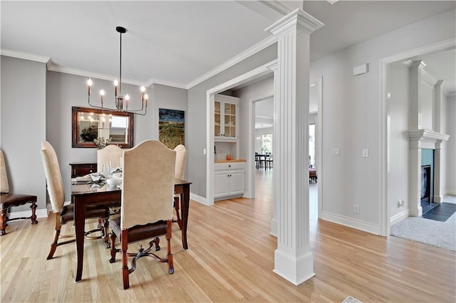 5010 W 161st Ter, Overland Park, KS 66085 - dining room featuring light wood-type flooring, ornate columns, crown molding, a chandelier, and a fireplace with flush hearth