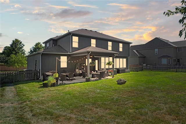 316 SE Hackamore Dr, Lees Summit, MO 64082 - back of house at dusk with a patio area, a fenced backyard, and an outdoor living space with a fire pit