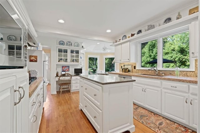 8422 Reinhardt Ln, Leawood, KS 66206 - kitchen featuring built in desk, a kitchen island, white cabinetry, light wood-type flooring, and stainless steel microwave