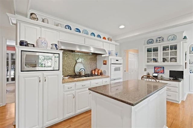8422 Reinhardt Ln, Leawood, KS 66206 - kitchen with ventilation hood, stainless steel appliances, white cabinetry, light wood-style floors, and decorative backsplash