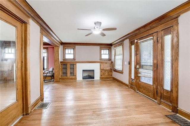 3509 Bellefontaine Ave, Kansas City, MO 64128 - unfurnished living room with ornamental molding, light wood-style flooring, a fireplace with flush hearth, and a ceiling fan