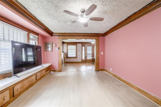 3509 Bellefontaine Ave, Kansas City, MO 64128 - unfurnished living room featuring ornamental molding, light wood-style flooring, a textured ceiling, a ceiling fan, and plenty of natural light