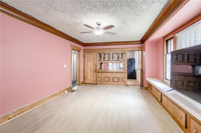 3509 Bellefontaine Ave, Kansas City, MO 64128 - spare room featuring light wood finished floors, a ceiling fan, crown molding, and a textured ceiling