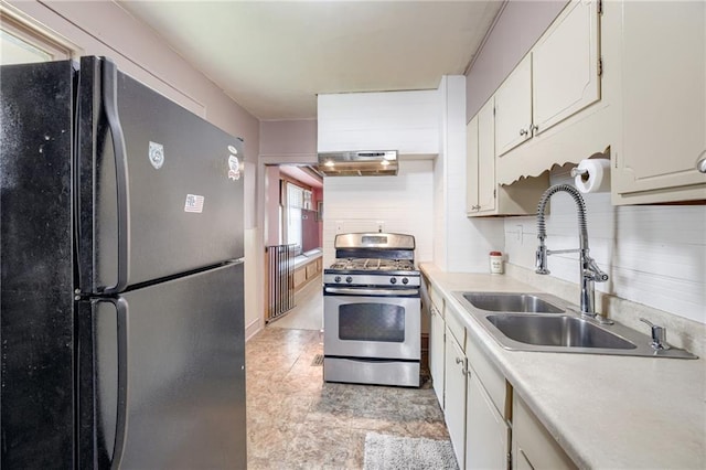 3509 Bellefontaine Ave, Kansas City, MO 64128 - kitchen with freestanding refrigerator, stainless steel range with gas stovetop, light countertops, under cabinet range hood, and white cabinetry