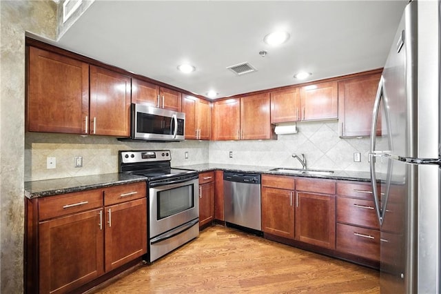 600 E Admiral Blvd Unit 1703, Kansas City, MO 64106 - kitchen featuring appliances with stainless steel finishes, dark stone countertops, light wood finished floors, backsplash, and recessed lighting