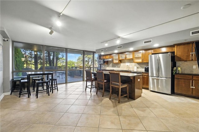 600 E Admiral Blvd Unit 1703, Kansas City, MO 64106 - kitchen featuring freestanding refrigerator, rail lighting, decorative backsplash, a breakfast bar, and a wall of windows