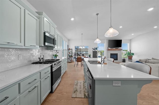 118 NW Grady Ct, Lees Summit, MO 64081 - kitchen featuring stainless steel appliances, decorative backsplash, open floor plan, a kitchen island with sink, and light wood-type flooring