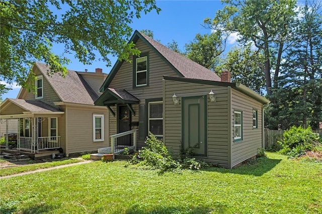 6016 Harrison St, Kansas City, MO 64110 - rear view of house featuring a chimney, a yard, and a shingled roof