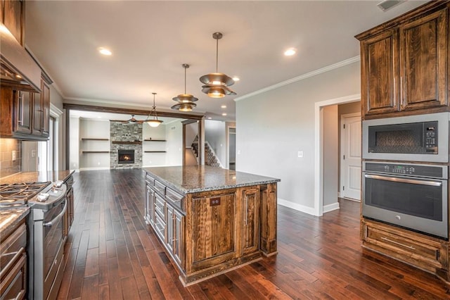 16699 S Chalet Dr, Olathe, KS 66062 - kitchen with appliances with stainless steel finishes, ornamental molding, dark wood finished floors, a fireplace, and dark stone counters