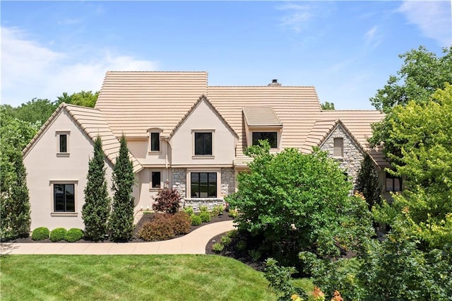 2616 W 112th St, Leawood, KS 66211 - tudor-style house with stone siding, a front yard, stucco siding, and a chimney