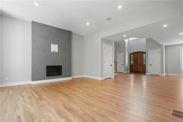 2616 W 112th St, Leawood, KS 66211 - unfurnished living room with light wood-type flooring, recessed lighting, a large fireplace, and arched walkways